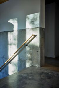 Top of stairs showing railing attached to exposed concrete wall.